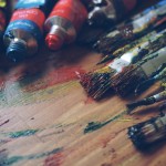 brushes and paints on wooden board
