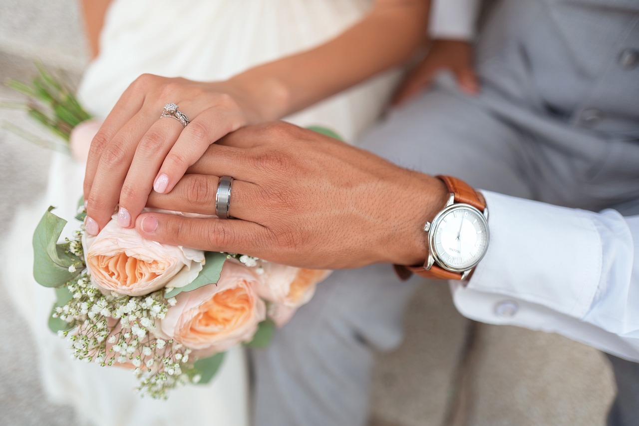 couple having rings in hand and flowers