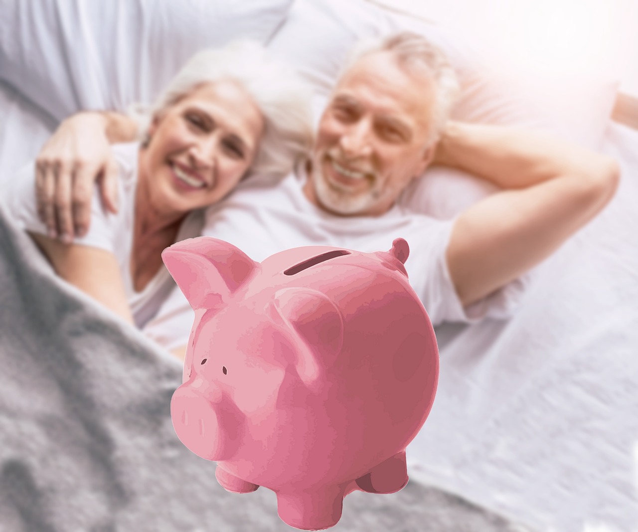 old couple lying on the bed and smiling by looking at the piggy bank