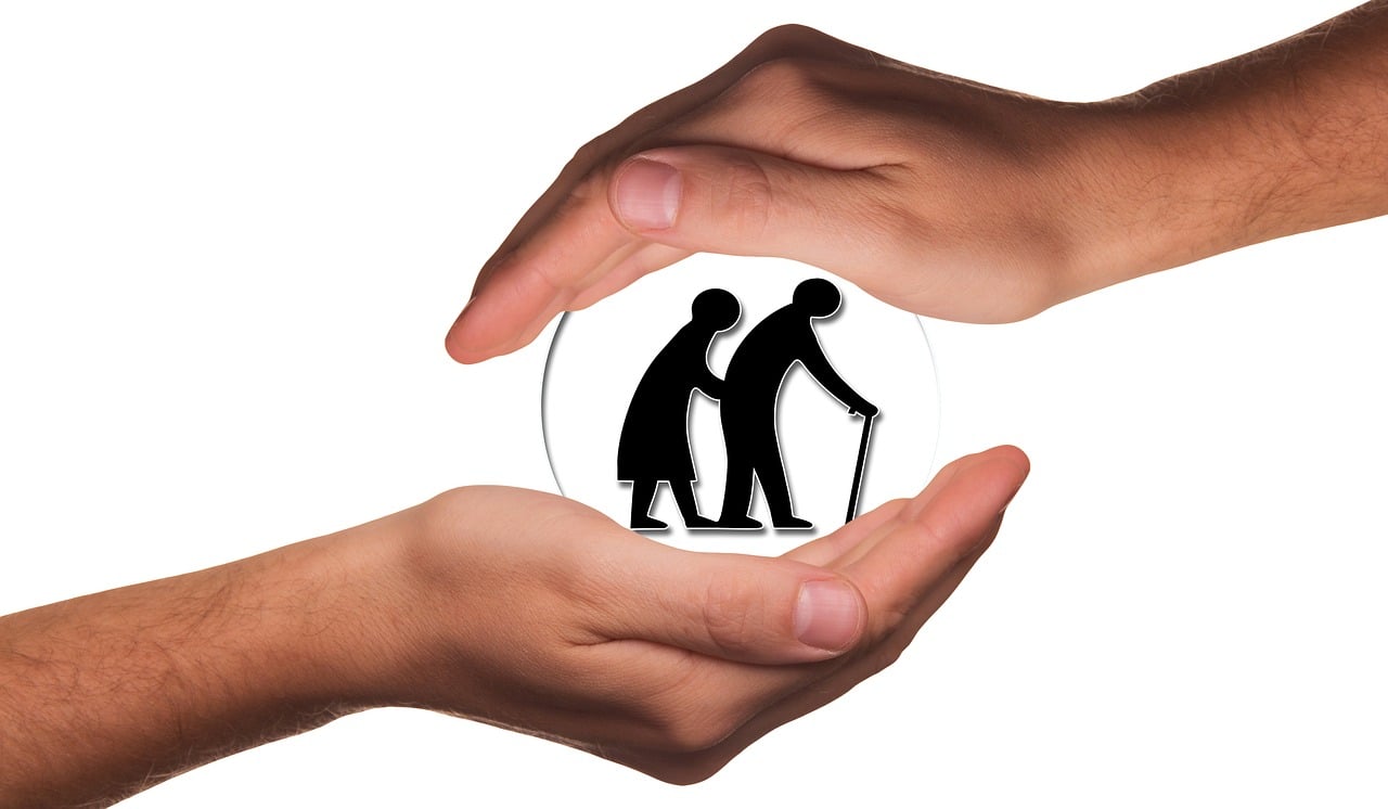 Two hands covering silhouettes of elderly people